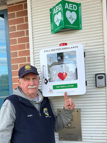 Lions club member in front of the defibrillator