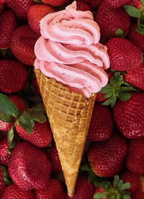 Waffle cone of strawberry icecream lying on strawberries