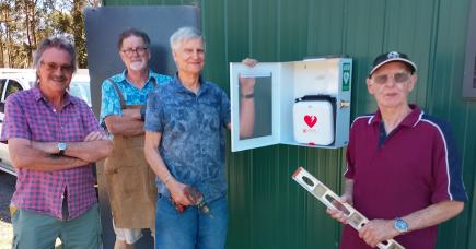 Mens Shed members beside the newly installed defibrillator